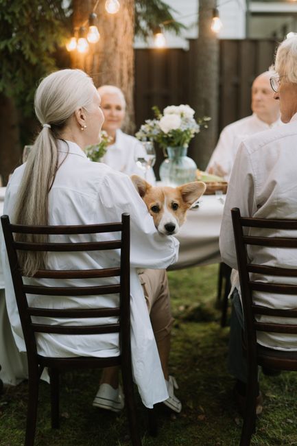 Family gathered around a table with a pet urn, framed photographs, flowers, and a favorite collar.